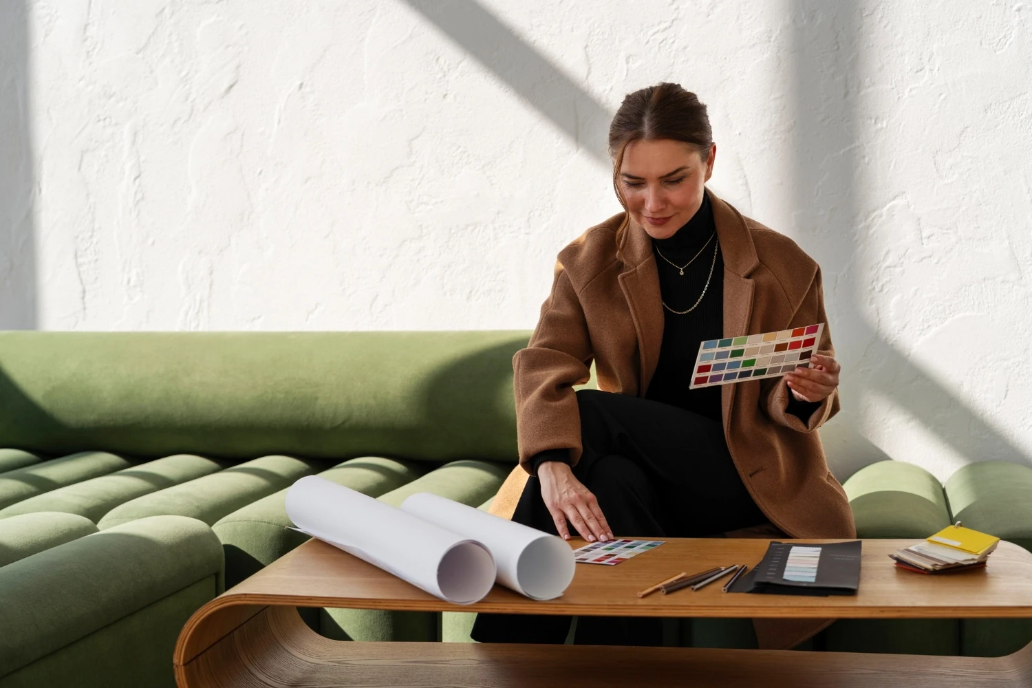 Interior designer selecting material samples beside drawings on a table